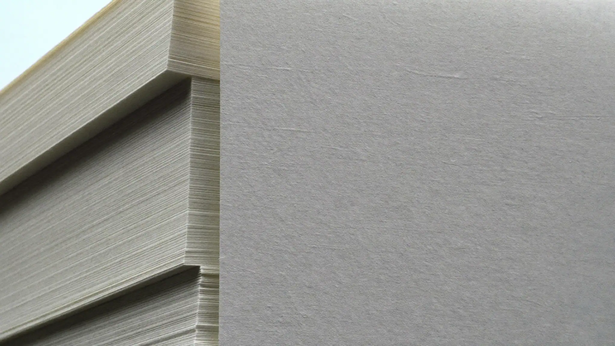 The edges of a tall stack of plain white paper, lit from the side so the sheets form fine parallel lines